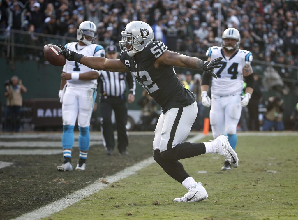 FILE - In this Sunday, Nov. 27, 2016, file photo, Oakland Raiders defensive end Khalil Mack (52) scores a touchdown after intercepting a pass by Carolina Panthers quarterback Cam Newton, left rear, during the first half of an NFL football game in Oakland, Calif. After becoming the first player ever named a first-team All Pro at two positions in one season in 2015, Raiders pass rusher Khalil Mack is taking his game to another level this year. (AP Photo/Tony Avelar, File)