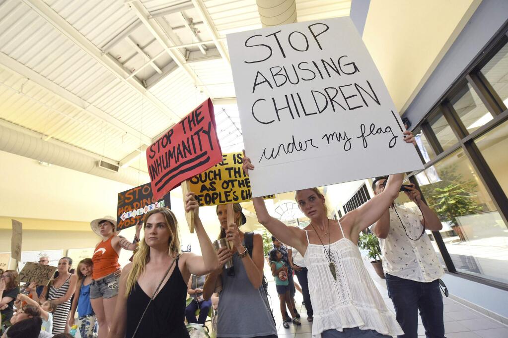 Kate Woodbury and other Wilmington residents hold up signs as they protested the Trump Administration's family separation policies during a Keep Families Together Rally outside of Rep. David Rouzer's office Wednesday June 20, 2018 at the New Hanover County Government Center in Wilmington, N.C. (Ken Blevins/The Star-News via AP)