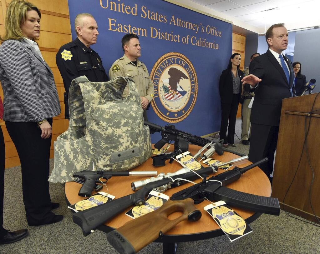 U.S. Attorney McGregor W. Scott, right, announces a federal grand jury four-count indictment against James Bowen, of Fresno, Calif., after federal authorities confiscated more than 200 guns after arresting him, at a news conference at the Coyle Federal Courthouse in Fresno, Calif.. Thursday, Jan. 25, 2018. Some of the seized firearms and body armor are displayed. Federal agents raided Bowen's Fresno home last week after he allegedly agreed to sell two assault-style rifles to an undercover officer. (John Walker/The Fresno Bee via AP)