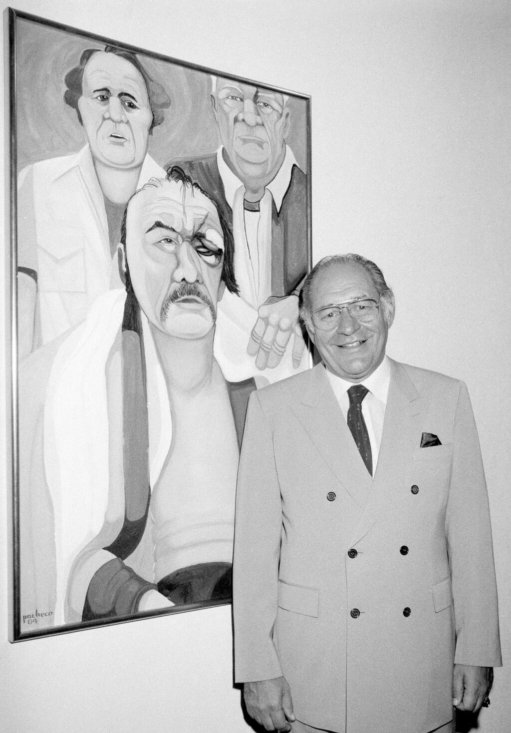 In this May 10, 1984, file photo, Ferdie Pacheco stands in front of his painting of boxer Chuck Wepner at Manhattan's Spectrum Fine Art Gallery in New York. Fernando “Ferdie” Pacheco, “The Fight Doctor” who served as Muhammad Ali's ringside physician, died Thursday morning, Nov. 16, 2017, at his Miami home after prolonged illness, his daughter, Tina Louise Pacheco, said. He was 89. (AP Photo/Lance Jeffrey)