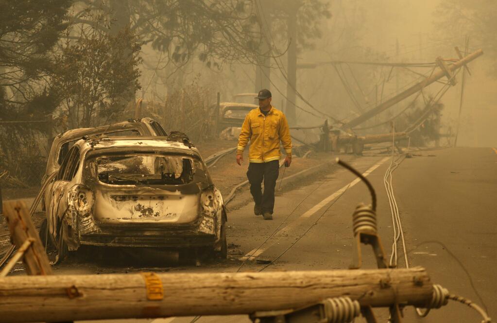 A Sonoma Valley firefighter inspects burned out cars to make sure they are clear of human remains, Friday, Nov. 9, 2018, in Paradise, Calif. (AP Photo/John Locher)