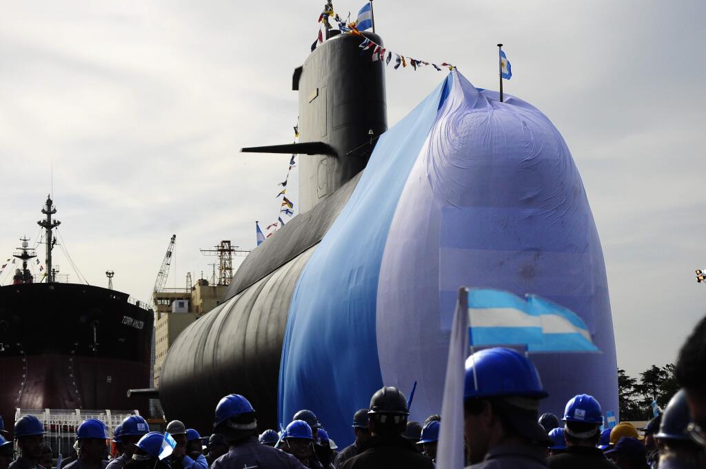 In this Sept. 27, 2011 photo, workers stand around the ARA San Juan submarine during a ceremony celebrating the first stage of major repairs at the Argentine Industrial Naval Complex (CINAR) in Buenos Aires. President Mauricio Macri said on Friday, Nov. 24, 2017 the international search for the submarine carrying 44 crew members that has been lost in the South Atlantic since Nov. 15 will continue and that the sub's disappearance will be investigated. (AP Photo/Mario Defina)