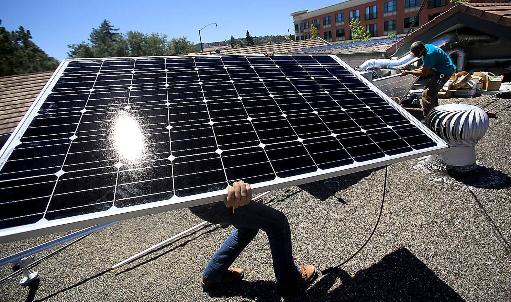 Solar installer Casandra Miller of Simply Solar of Petaluma moves a solar panel in to location on the roof of a Petaluma business, Wednesday Aug. 12, 2015. At right is co-worker Will Anjo. (Kent Porter / Press Democrat) 2015