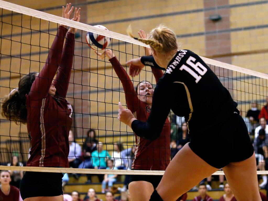 Windsor's Allison Post (16), right, spikes the ball between Cardinal Newman's Megan Vice (7), left, and Julianna Filice (3) during a varsity volleyball game between Cardinal Newman and Windsor high schools on Tuesday, October 25, 2016. (Alvin Jornada / The Press Democrat)