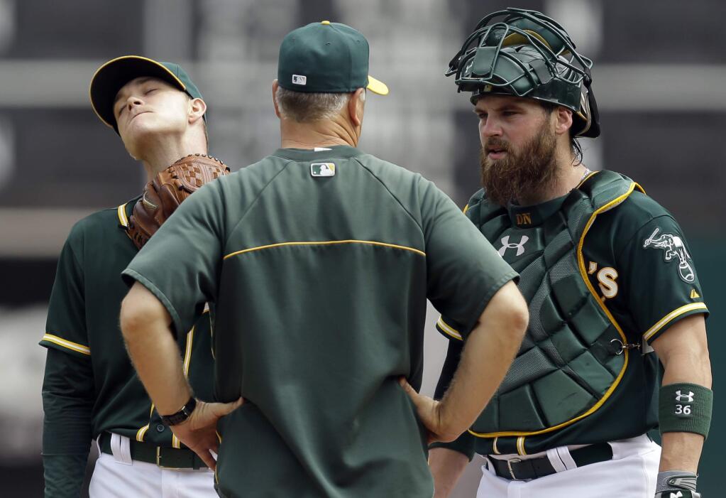 Oakland Athletics' Sonny Gray, left, is visited by pitching coach Curt Young, center, and catcher Derek Norris in the first inning of a baseball game against the Texas Rangers Thursday, Sept. 18, 2014, in Oakland. (AP Photo/Ben Margot)