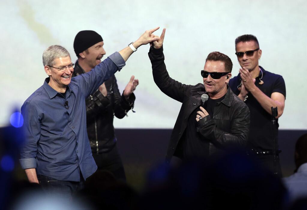 In this Sept. 9, 2014 file photo, Apple CEO Tim Cook, left, greets Bono from the band U2 after they preformed at the end of the Apple event on Tuesday, Sept. 9, 2014, in Cupertino, Calif. Apple unveiled a new Apple Watch, the iPhone 6 and Apple Pay and U2 offered iTunes customers a free download of their latest album, 'Songs of Innocence.' (AP Photo/Marcio Jose Sanchez)