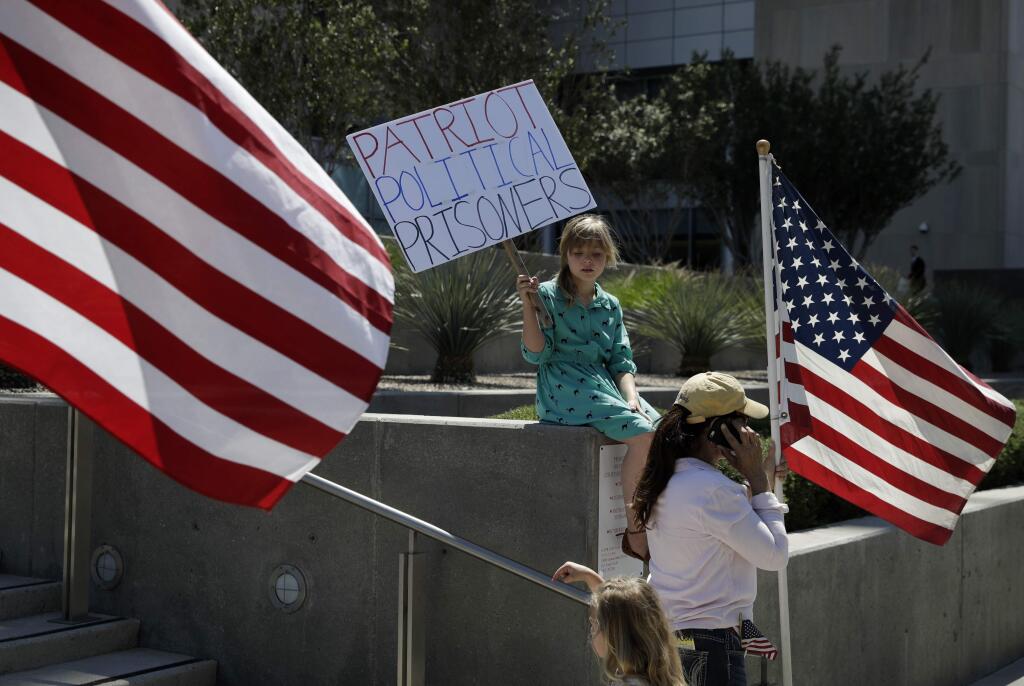Nine-year-old Paylynn Lawrimore holds up a sign in support of defendants on trial in federal court, Wednesday, April 12, 2017, in Las Vegas. A federal jury in Las Vegas heard closing arguments in the trial of six men accused of wielding weapons to stop federal agents from rounding up cattle near Nevada rancher Cliven Bundy's property in 2014. (AP Photo/John Locher)