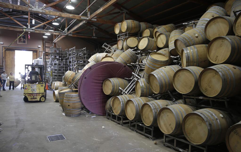Cellar workers continue cleanup after a number of barrels toppled following an earthquake at the Saintsbury winery Sunday, Aug. 24, 2014, in Napa, Calif. Winemakers in California’s storied Napa Valley woke up to thousands of broken bottles, barrels and gallons of ruined wine as a result of the earthquake. (AP Photo/Eric Risberg)