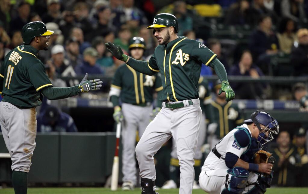 Oakland Athletics' Matt Joyce, center, shares congratulations at home on his two-run home run with Rajai Davis as Seattle Mariners catcher Carlos Ruiz looks down during the ninth inning of a baseball game Tuesday, May 16, 2017, in Seattle. (AP Photo/Elaine Thompson)