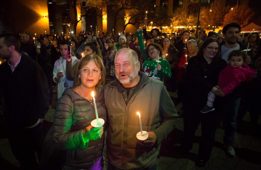 Coby and Matt Stockton react at the christmas tree lighting while holding candles in remembrance of loved ones who have passed during downtown Santa Rosa's annual tree lighting event – Winter Lights Friday November, 25, 2016. (Jeremy Portje / For The Press Democrat)