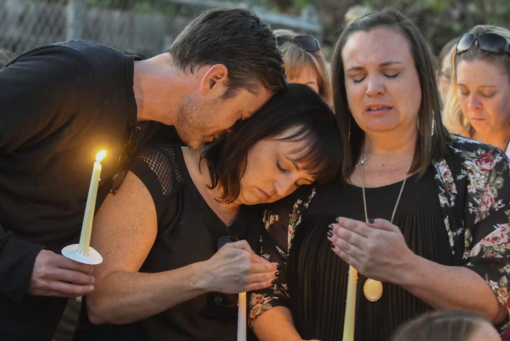 Ryan DiDonato, left, lays his head on Heather Gyurina, center, and Tracy Gyurina, right, during a candlelight vigil for their friend Teresa Nicol Kimura at Sierra Vista Elementary in Placentia, Calif., Sunday, Oct. 8, 2017. (Michael Kitada/The Orange County Register via AP)