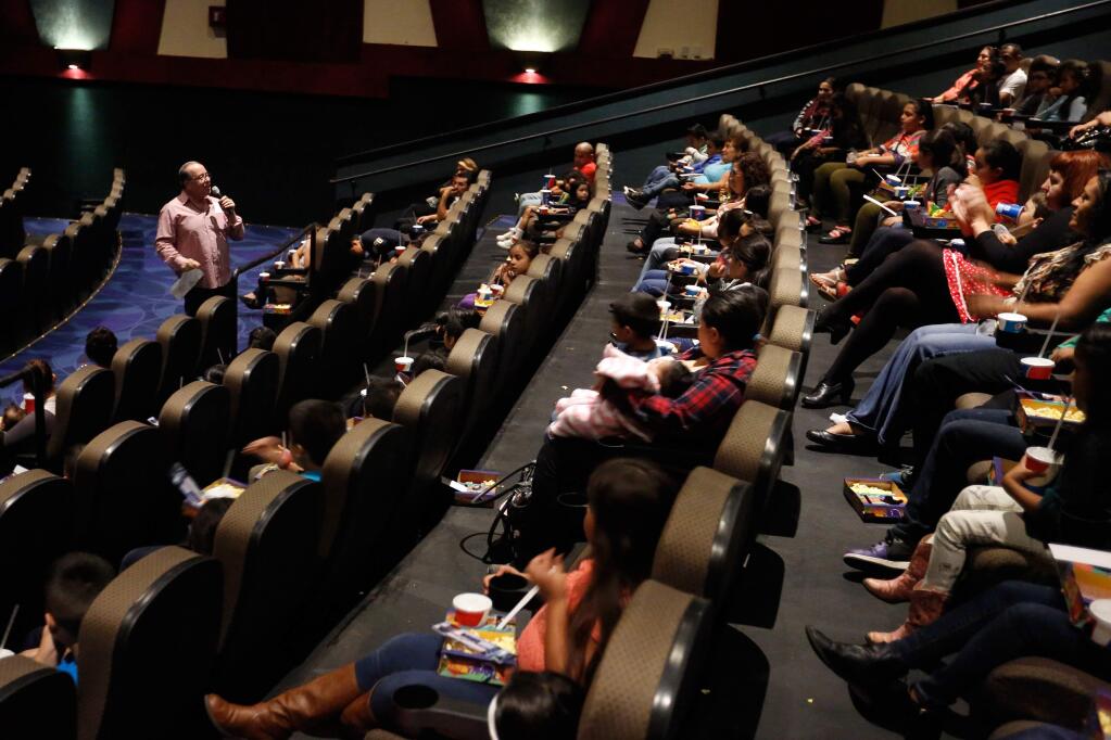 David Waisbein, standing at left, welcomes Roseland School District elementary students and parents to a showing of the movie 'Pan' which he provided tickets for, at Airport Cinemas in Santa Rosa, California on Saturday, October 17, 2015. (Alvin Jornada / The Press Democrat)