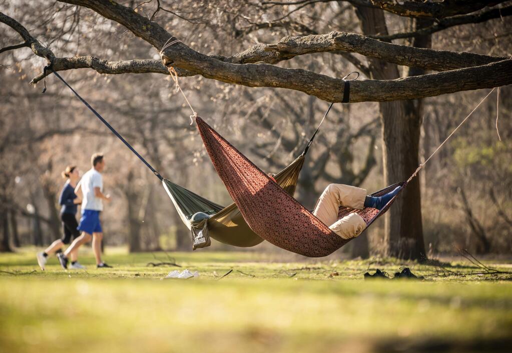 A couple has made themselves comfortable in hammocks in Tiergarten Park in the centre of Berlin, Germany, Tuesday, March 17, 2020. The coronavirus crisis is driving many walkers into the parks and out into the fresh air. For most people, the new coronavirus causes only mild or moderate symptoms, such as fever and cough. For some, especially older adults and people with existing health problems, it can cause more severe illness, including pneumonia. (Michael Kappeler/dpa via AP)