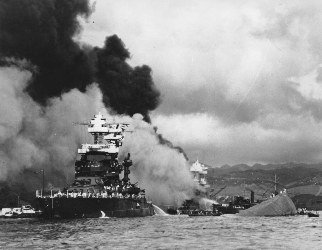 FILE - In this Dec. 7, 1941 file photo, part of the hull of the capsized USS Oklahoma is seen at right as the battleship USS West Virginia, center, begins to sink after suffering heavy damage, while the USS Maryland, left, is still afloat in Pearl Harbor, Oahu, Hawaii. (AP Photo/U.S. Navy, File)