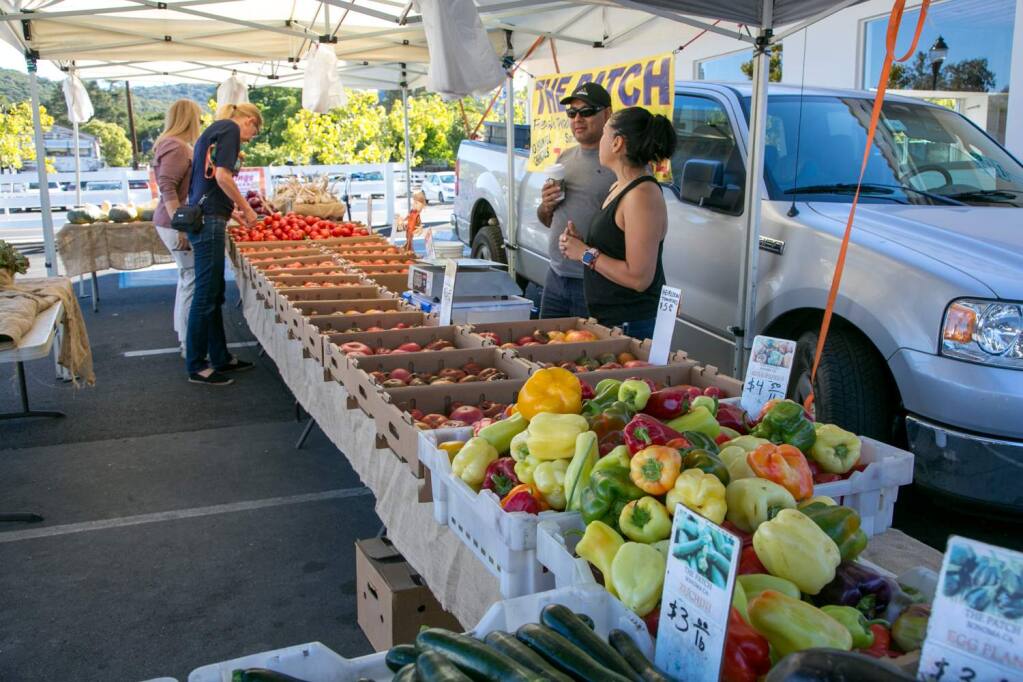 Lazaro Calderon and Mary Serrato sell produce from The Patch at the Springs Community Farmers Market Sunday, Oct. 7, 2018. Brisk winds later in the day prompted the covering tents to be taken down. (Julie Vader / special to the Sonoma Index-Tribune)