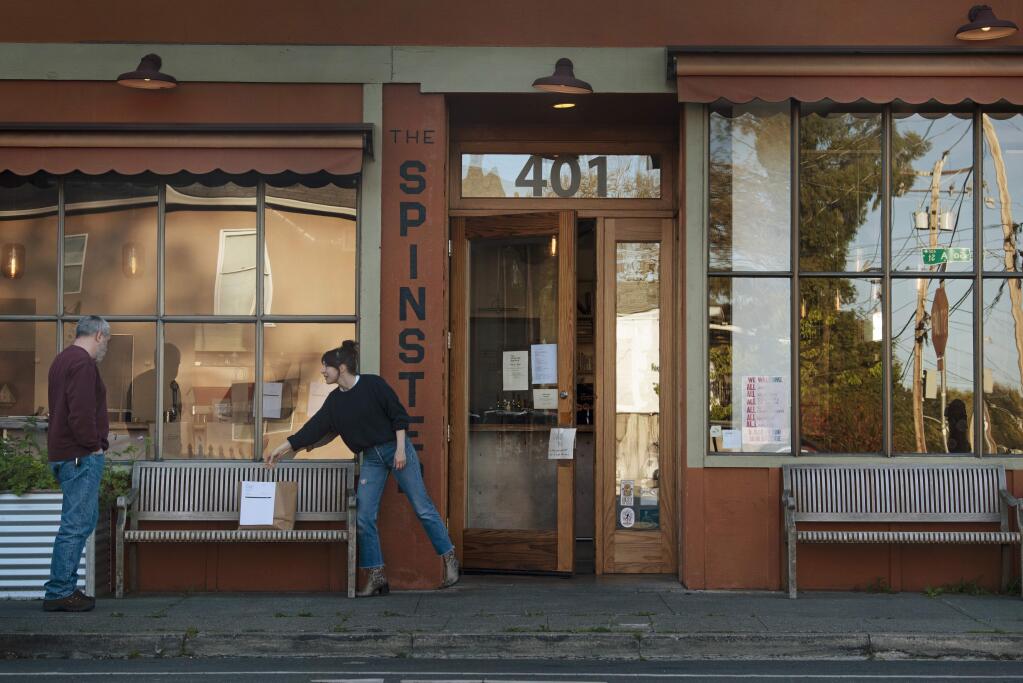 Ela Jean Beedle, right, placing a dinner order on a bench to practice social distancing for a customer receiving his meal for curbside pick up only at The Spinster Sisters restaurant in Santa Rosa, California on April 2, 2020.(Photo: Erik Castro/for Sonoma Magazine)