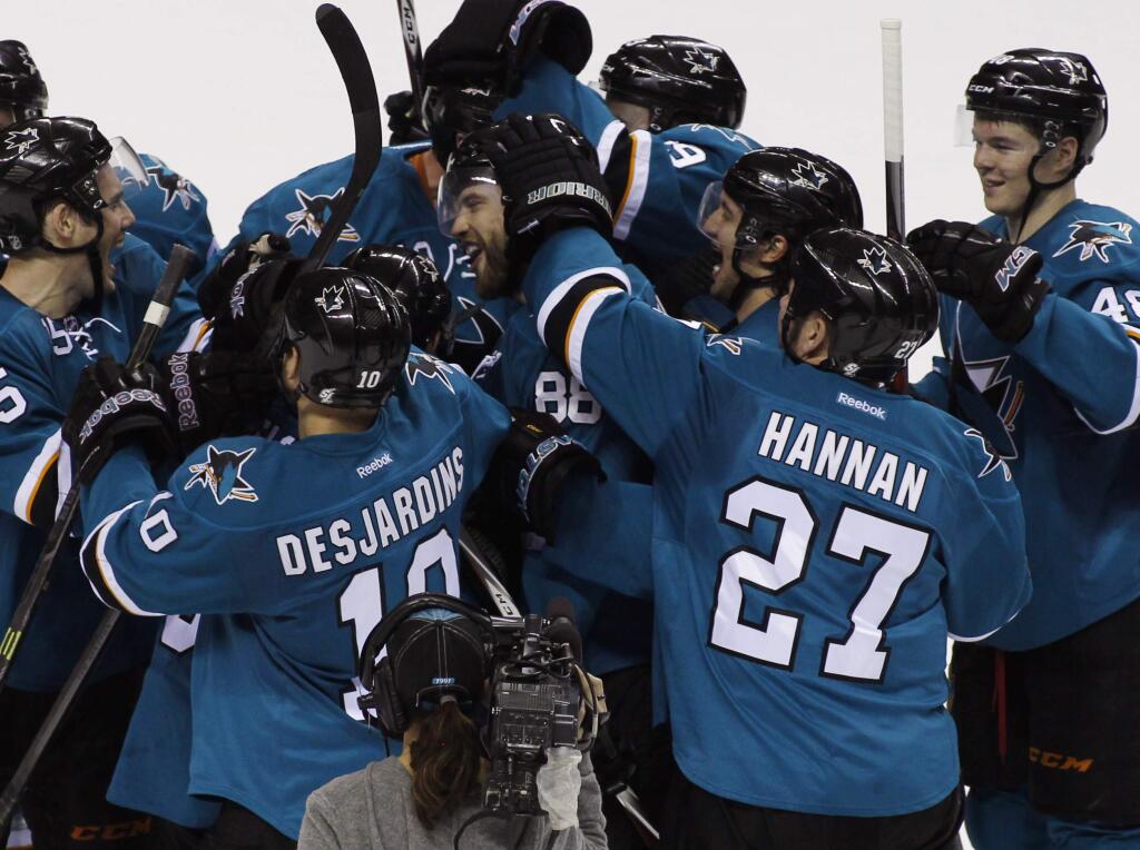 San Jose Sharks' Brent Burns, center, celebrates with teammates after scoring the winning goal in overtime against the St. Louis Blues in a game Saturday, Dec. 20, 2014, in San Jose. (AP Photo/George Nikitin)