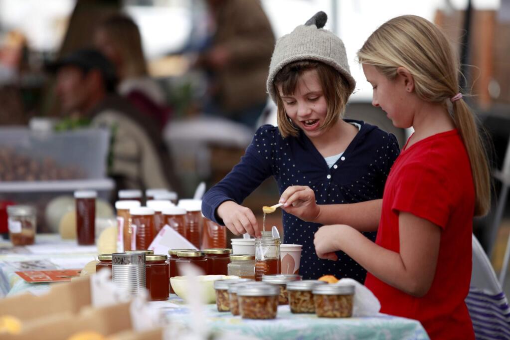 Gwyneth Barker, 7, left, and Amber Vanoni, 8, taste honey from the Beelove Honey during the West End Farmers Market in Santa Rosa, California on Sunday, November 3, 2013. (BETH SCHLANKER/ The Press Democrat)
