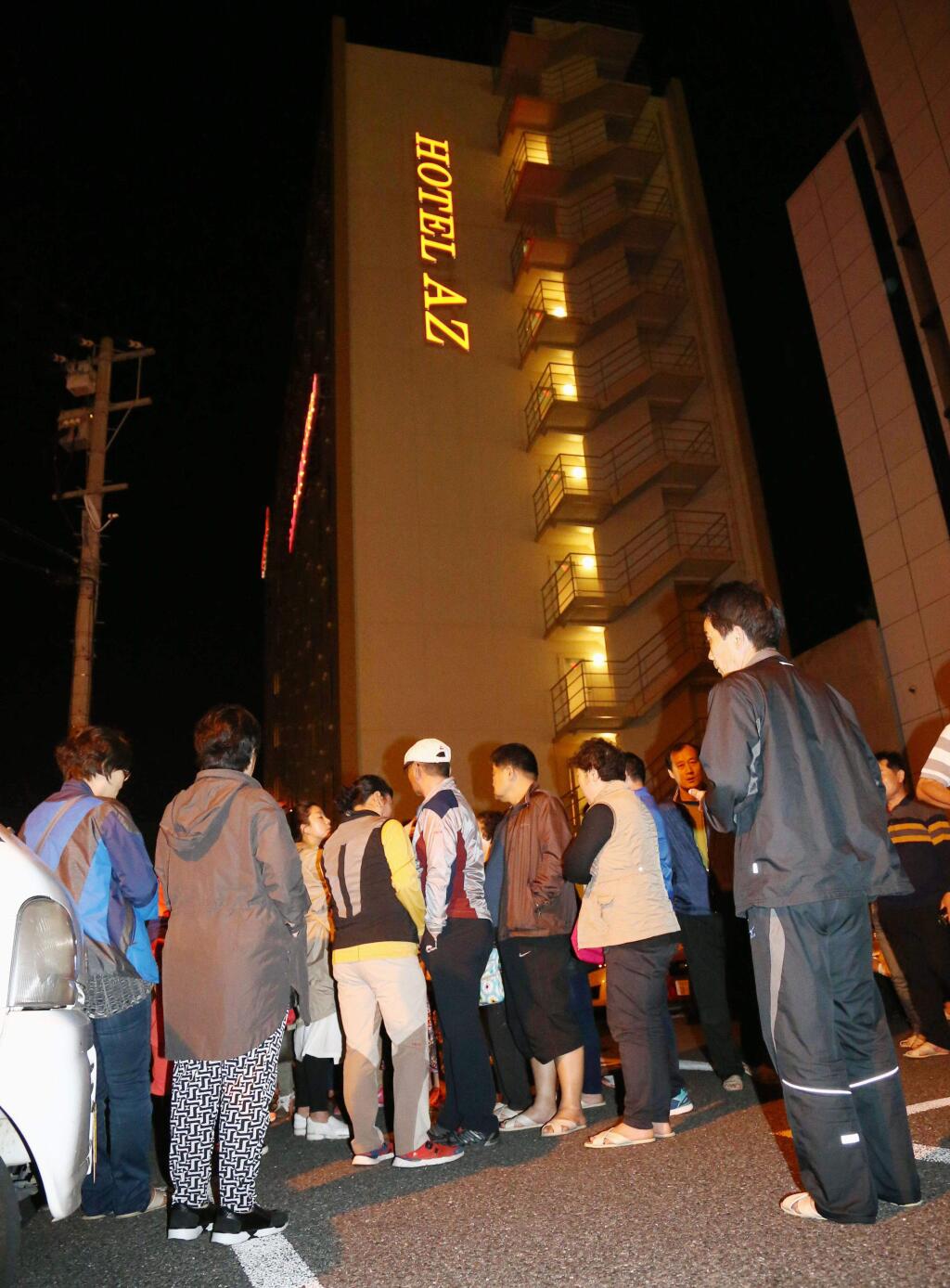 People gather outside a hotel after an earthquake in Kumamoto, southern Japan, Thursday, April 14, 2016. A powerful earthquake with a preliminary magnitude of 6.4 has struck southern Japan. Japan's Meteorological Agency said the quake hit at 9:26 p.m. (1226 GMT) and was centered in the Kumamoto prefecture. (Kyodo News via AP)