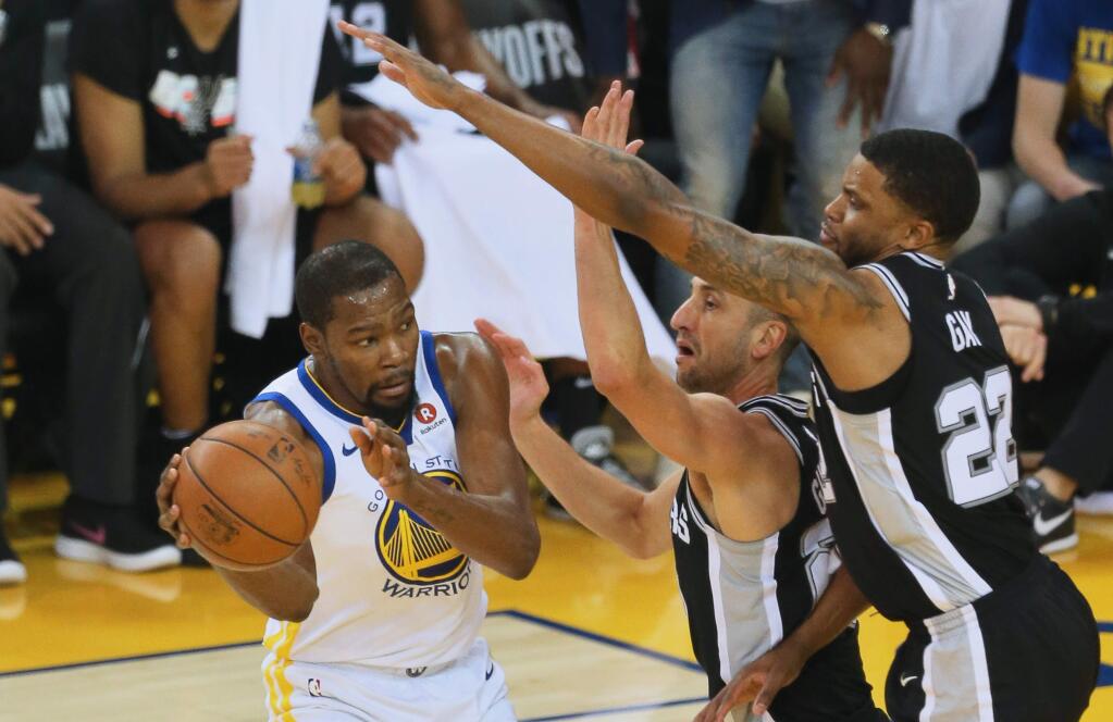 Golden State Warriors forward Kevin Durant passes out of a double-team by San Antonio Spurs Manu Ginobili and Rudy Gay in Oakland on Saturday, April 14, 2018. (Christopher Chung / The Press Democrat)