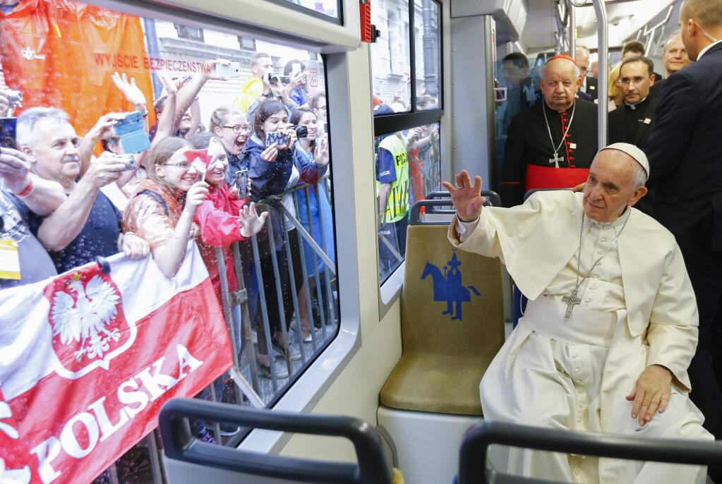 Pope Francis waives to a cheering crowd of faithful as he drives by in a public transportation tram he used to reach the venue of the World Youth Days in Krakow, Poland, Thursday, July 28, 2016. Pope Francis is in Poland for a five-day pastoral visit and to attend the 31st World Youth Days. (Stefano Rellandini/Pool photo via AP)