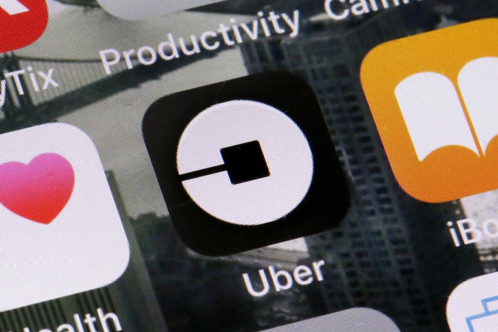 FILE - This Tuesday, June 12, 2018, file photo shows the Uber app on a phone in New York. On Monday, July 9, 2018, Uber said it is getting into the scooter-rental business, and is investing in Lime, a startup based in San Mateo, California. (AP Photo/Richard Drew, File)