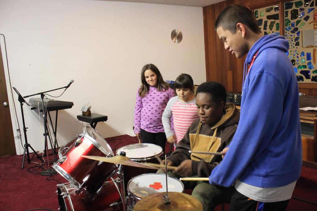 Kate Hoover/For the Argus-CourierVolunteer youth instructor Kenneth Santiago shows students in the Petaluma Salvation Army's music program how to play the drums.