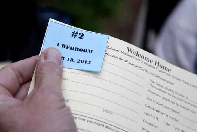 Danny Hall, property manager of USA Multifamily Management Inc., hands out numbers to people as they wait in line to apply for the new Tierra Springs Apartments. for those with moderate to middle incomes, in Santa Rosa on Wednesday, Feb. 18, 2015. (BETH SCHLANKER/ PD FILE)