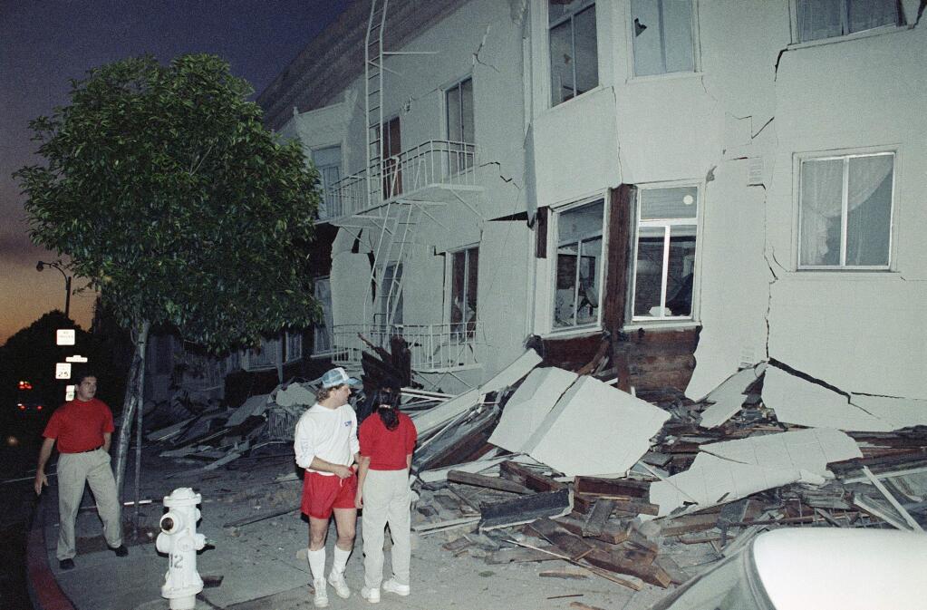 FILE - In this Oct. 17, 1989, file photo, residents look over a building in the Marina area of San Francisco which was severely damaged by a major earthquake which rocked the Bay area. A newspaper analysis finds the San Francisco Bay Area is falling behind on efforts to retrofit buildings that are vulnerable to collapse during a major earthquake. The Los Angeles Times reported Sunday, April 22, 2018, that there are up to 3,000 brittle concrete buildings in San Francisco, yet the city doesn't have a list of where they are located. The building type is one of the deadliest in quakes. (AP Photo/Peter DaSilva, File)