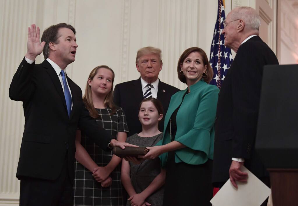 President Donald Trump, center, listens as retired Supreme Court Justice Anthony Kennedy, right, ceremonially swears-in Supreme Court Justice Brett Kavanaugh, left, in the East Room of the White House in Washington, Monday, Oct. 8, 2018. Kavanaugh's wife Ashley watches, second from right with daughters Margaret, left, and Liza. (AP Photo/Susan Walsh)
