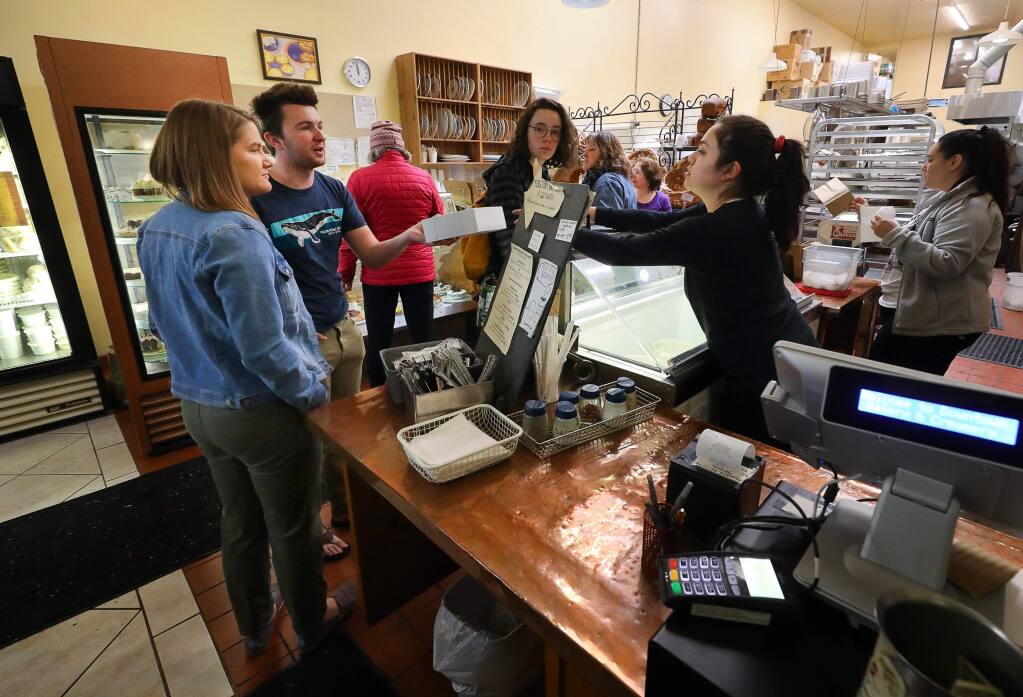 Alejandra Garcia, right, hands an order to Sean Lange and Melissa Maiste at the Downtown Bakery & Creamery in Healdsburg on Friday, March 13, 2020. (Christopher Chung/ The Press Democrat)