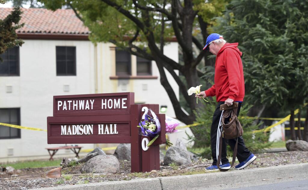 Resident Tom Parkinson places flowers outside Pathway Home, a veterans service organization on the campuse of the California Veterans Home, where three staff members were shot and killed. (JOSH EDELSON / Associated Press)