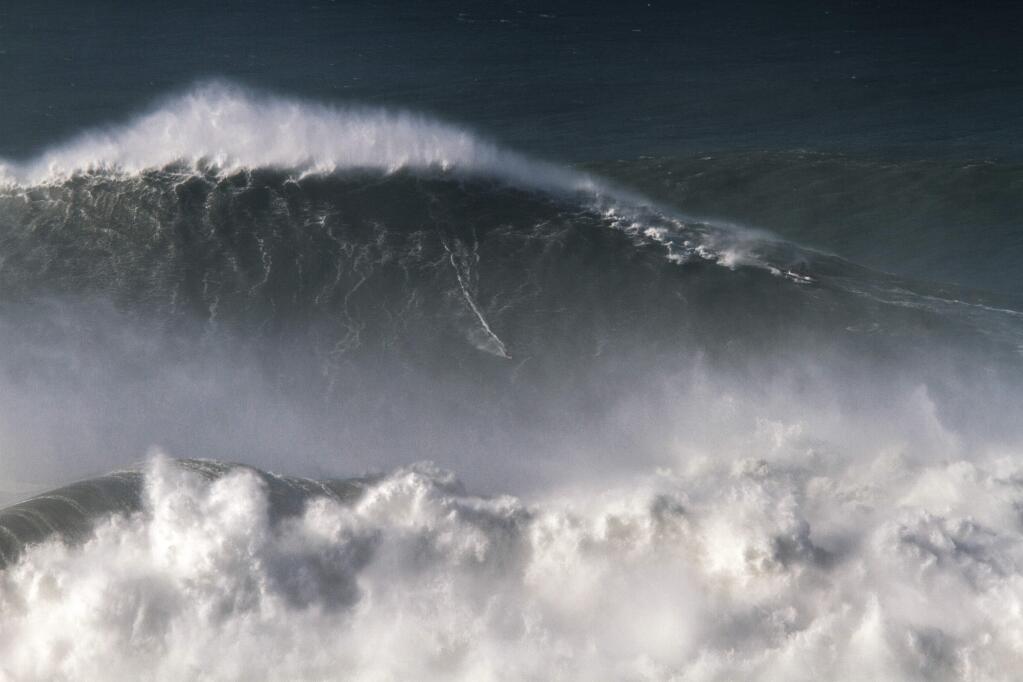 In this photo taken Nov. 8 2017, Brazilian surfer Rodrigo Koxa rides what has been judged the biggest wave ever surfed, at the Praia do Norte, or North beach, in Nazare, Portugal. On Saturday, April 28 2018, the World Surf League credited Koxa with a world record for riding the biggest wave ever surfed and said that its judging panel determined the wave was 80 feet (24.38 meters). (AP Photo/Pedro Cruz)