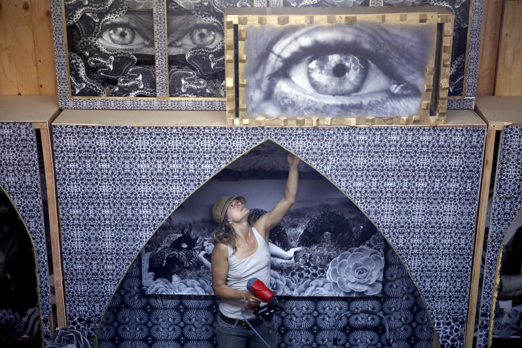 Artist Natalia Bertotti works to finish the 'Totem of Confessions', a chapel made of wood and covered with photographs and ornamentation, for Burning Man. Photo taken at a warehouse on Wednesday, July 8, 2015 in Petaluma, California . (BETH SCHLANKER/ The Press Democrat)