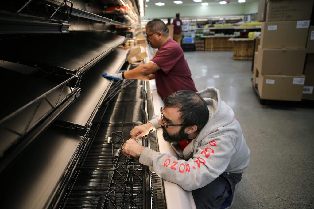 Employees Adam Vietro and Freddie Ramirez, rear, work to install shelving in the refrigerated section of Trader Joe's at 3225 Cleveland Ave. in preparation for the reopening of the store. Photo taken in Santa Rosa on Wednesday, Nov. 14, 2018. (BETH SCHLANKER/ PD)