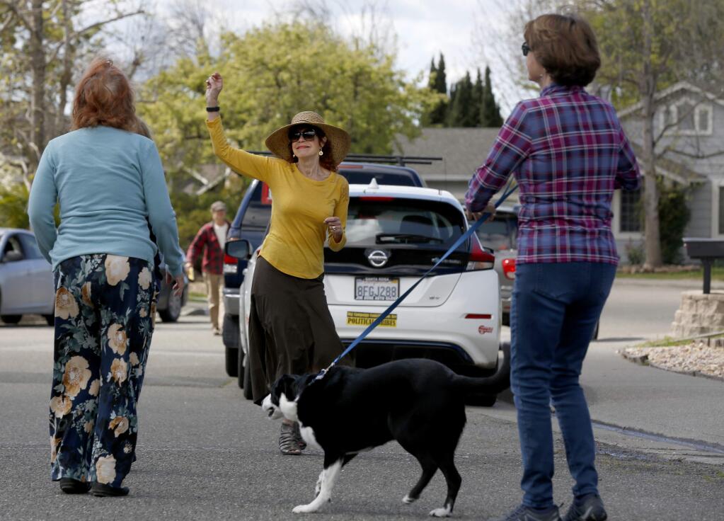 Judy Heikel, center, dances to the music of the band Los Gu'achis during a free pop-up concert for neighbors on Northstar Dr. in Petaluma, California on Thursday, March 26, 2020. (BETH SCHLANKER/The Press Democrat)