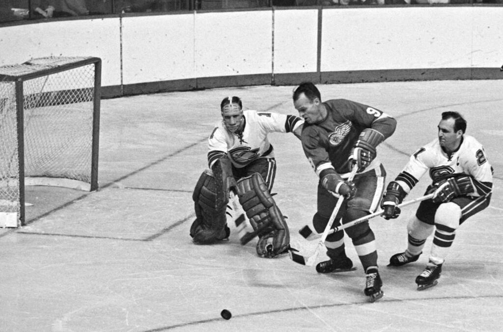 In this Oct. 26, 1967 file photo, California Seals goalie Charlie Hodge, left, knocks the puck away as Detroit Red Wings star Gordie Howe tries a shot on goal as the Seals' Bob Baun comes in at right. (AP Photo/Preston Stroup, File)