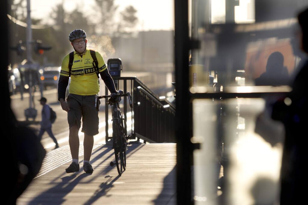 Jonathan Cole, headed to work in San Anselmo, walks with his bike at the SMART station in Petaluma, on Wednesday, November 29, 2017. (BETH SCHLANKER/ The Press Democrat)