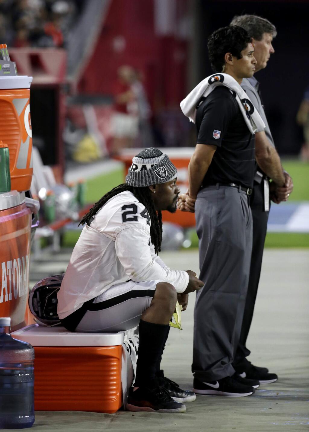 FILE - In this Aug. 12, 2017, file photo, Oakland Raiders running back Marshawn Lynch sits during the national anthem prior to the team's NFL preseason football game against the Arizona Cardinals in Glendale, Ariz. What started as a protest against police brutality has mushroomed a year later into a divisive debate over the future of former San Francisco 49ers quarterback Colin Kaepernick who refused to stand for the national anthem and now faces what his fans see as blackballing for speaking out in a country roiled by racial strife. Other prominent NFL players, such as Lynch, have sat out or demonstrated during anthems this preseason. (AP Photo/Rick Scuteri, File)