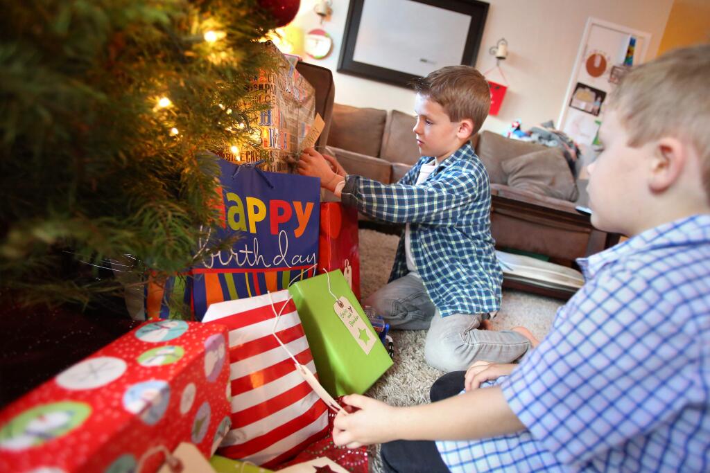 Gavin King, left, who will be turning seven on Christmas Day, reads the tag on one of his birthday presents under the Christmas tree while checking out presents with his brother, Brendan, 5, at their home in Petaluma on Wednesday, December 24, 2014. (Christopher Chung/ The Press Democrat)