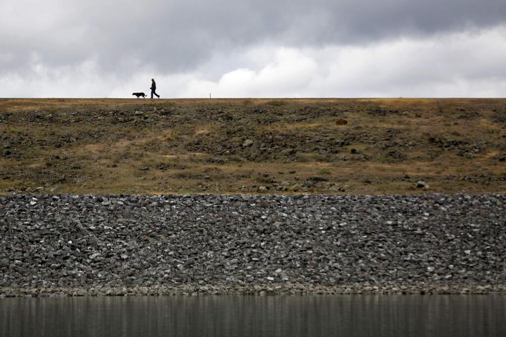 A man walks a dog atop the dam at Lake Mendocino in March, 2015. (BETH SCHLANKER/ The Press Democrat)