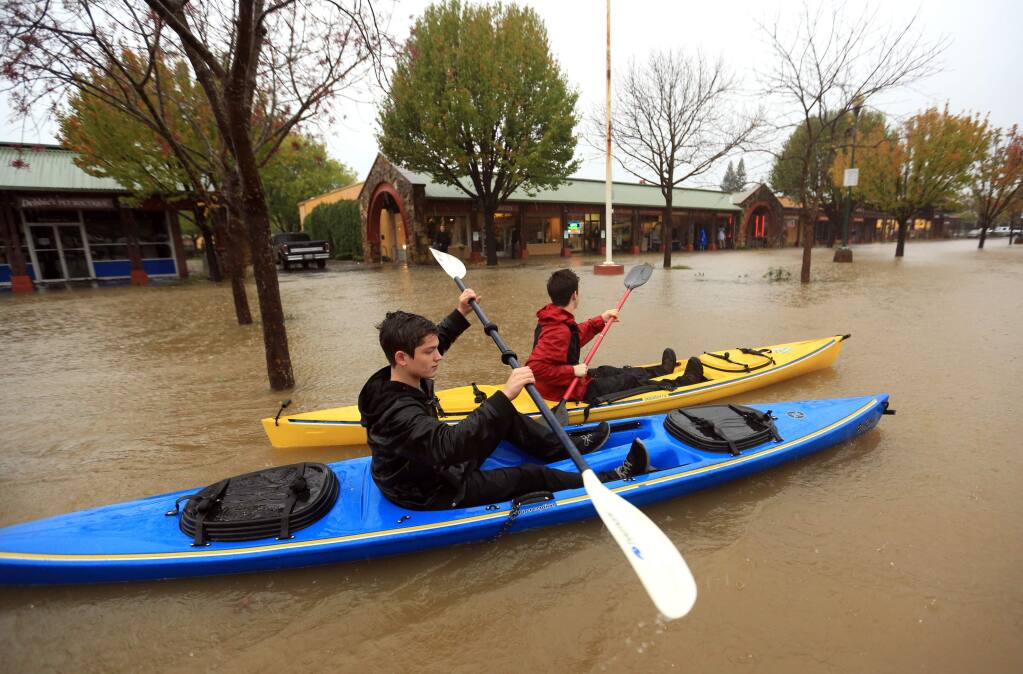 Kayakers make their way through the Healdsburg Center on Center Street to check out the flooding, Thursday, Dec. 11, 2014. (KENT PORTER/ PD)