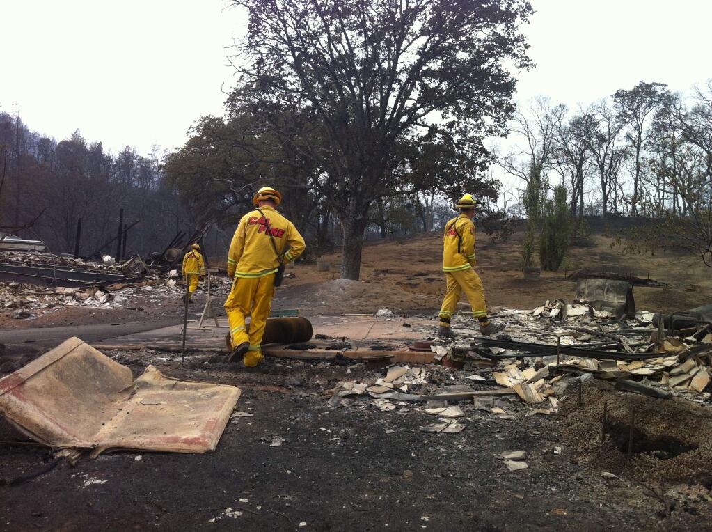 Cal Fire walks through the ruins on the outskirts of Middletown, Monday, Sept. 14, 2015. (BETH SCHLANKER / PRESS DEMOCRAT)