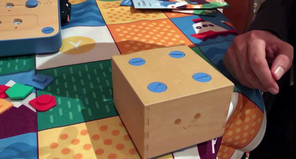 In this Jan. 9, 2018, image made from a video, the Cubetto robot moves across a table following commands input into a board using blocks at the CES gadget show in Las Vegas. The “Cubetto” block on wheels responds to where chip-embedded pieces are put on a wooden board. Different colors represent different commands, for example, to 'go straight' or 'turn left.' (AP Photo/Ryan Nakashima)