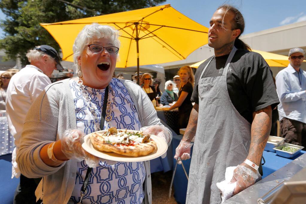 Robin Finkelstein, left, of Santa Rosa beams after being complimented on making one of the best looking pizzas of the day, as Worth Our Weight grillmaster Lukas Falcon, right, looks on, during the North Coast Food and Wine Festival at SOMO Village in Rohnert Park, California, on Saturday, June 10, 2017. (Alvin Jornada / The Press Democrat)