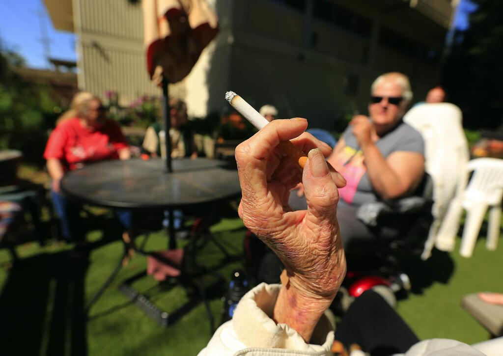 Smokers who live in the Bethlehem Towers in Santa Rosa light up outside in a designated smoking area in 2015. (JOHN BURGESS/ PD)