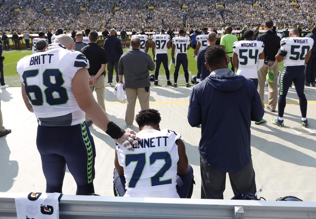 Seattle Seahawks' Michael Bennett remains seated on the bench during the national anthem before an NFL football game against the Green Bay Packers Sunday, Sept. 10, 2017, in Green Bay, Wis. (AP Photo/Jeffrey Phelps)