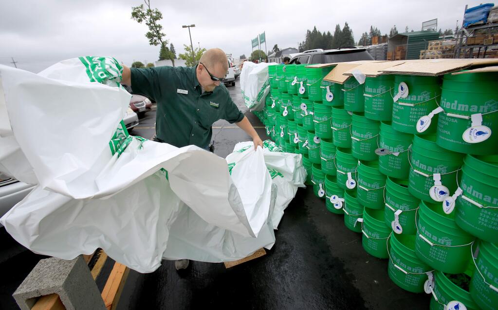JP Pizzio of Friedman's Home Improvement covers buckets during a free Drought Drive-up giveaway , which included dye-tabs, aerators and tips on how to save water, Thursday July 9, 2015. (Kent Porter / Press Democrat) 2015