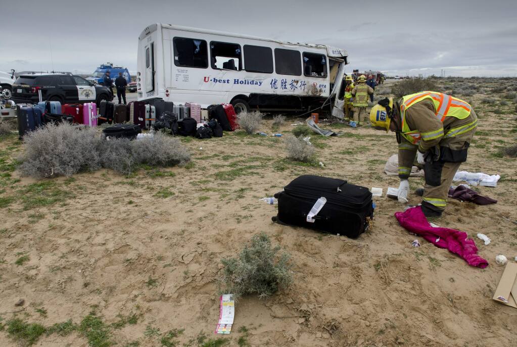 Firefighters sort through the debris after a deadly crash involving a tour bus on State Route 58 near Kramer, Calif., Monday Feb. 27, 2017. A tour bus crossed into oncoming traffic and hit two cars head-on, in a deadly crash that injured over a dozen, according to the California Highway Patrol. (James Quigg/The Daily Press via AP)