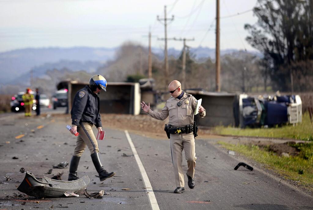 CHP officers Bob Powers, left, and Jeff Engwall investigate the scene of an accident on River Road after a van collided with a truck carrying dirt and rock in Santa Rosa on Monday, Jan. 5, 2015. (BETH SCHLANKER/ PD)